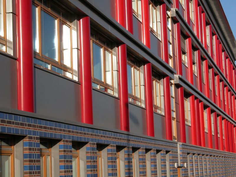 Fassade des Sartre-Gymnasiums mit roten Stützen und blauen Fliesen